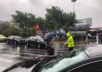 Polisi mengatur lalu lintas di tengah hujan lebat di Shanghai, Selasa (13/9). FOTO: SHINE
